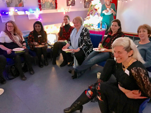 7 Relational Spaces practitioners sitting and watching a performance at the 2018 Christmas party