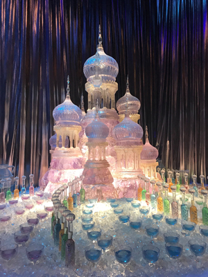 Ice sculpture surrounded by glasses with blue liquid